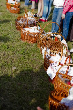 Kutsal su ile kutsanmış Paskalya pastaları. Paskalya için işlenmiş havlularla dolu birkaç sepet. Kadınlar sepetlerin yanında duruyorlar. Mumlar yanıyor..