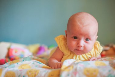 Sarı elbiseli bir bebek dairedeki bir soyunma masasında yatıyor. İlk çocuk becerileri. Aylarca çocuk gelişimi. Hayatın ilk ayı sağlıklı bebek. Kendinden emin, düşünceli bir bebek. Yüzünde ciddi bir duygu ya da ifade var. Seçici odak