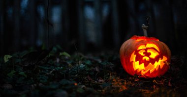 Karanlık bir ormanda oyulmuş, ürkütücü, Cadılar Bayramı balkabağı.