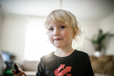 A happy, young girl with blonde hair smiles directly at the camera.