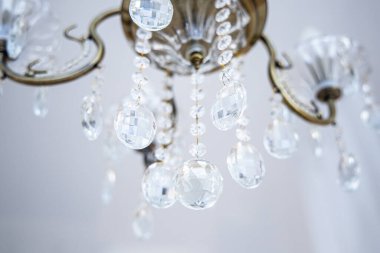 Beyaz tavandan sarkan altın çerçeveli zarif kristal avize.