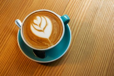 Ahşap masada bir fincan latte sanat kahve