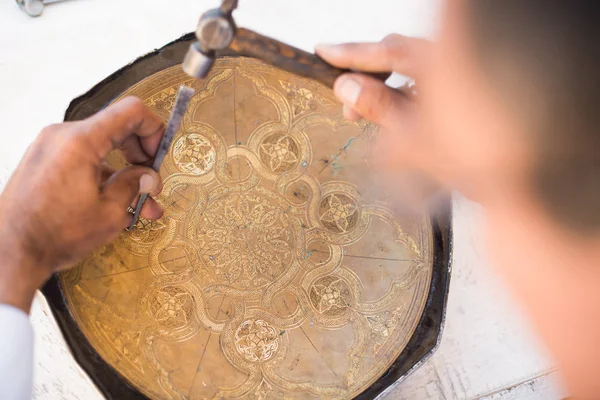 craftsman engraving patterns on the tray. masters of Central Asia. manual copper minting