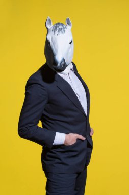 A man in a suit and a horse mask on a yellow background. Conceptual business background clipart