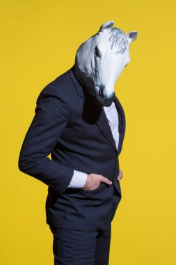 A man in a suit and a horse mask on a yellow background. Conceptual business background clipart