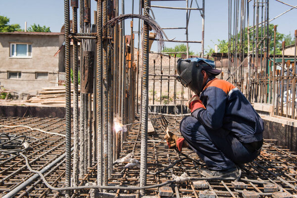 construction worker welding metal rebar for the pouring of foundation. candid, real people