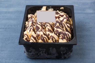 iştah açıcı dondurma dekoratif mavi arka plan üzerinde bir fiyat etiketi ile plastik bir kap içinde