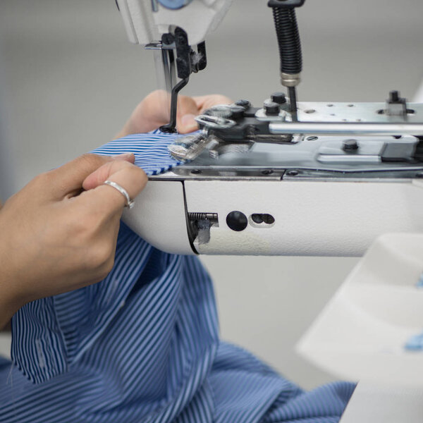 the woman in the workshop sews buttons to the shirt