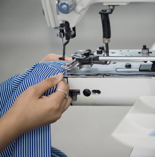 the woman in the workshop sews buttons to the shirt