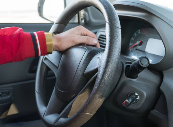 men\'s hand with a watch on the steering wheel of a modern car