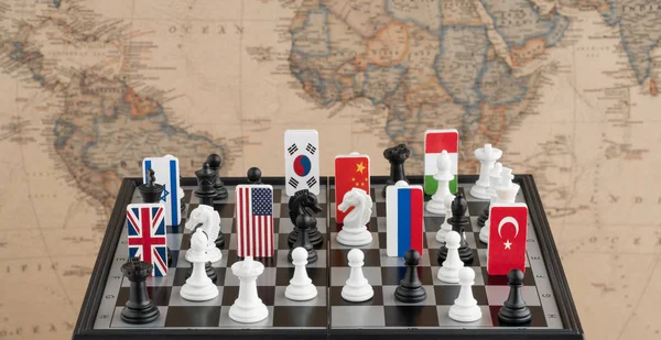 Country flag symbols on the chessboard with figures on the background of the political map of the world. Conceptual photo of a political game.