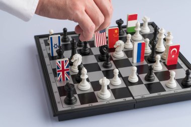 Politician's hand moves a chess piece with a flag. Conceptual photo of a political game. retaliatory move USA clipart