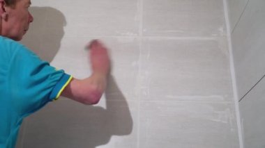 İşçi ıslak sünger karolar arasında dikişleri çöp. Bitirme işleri, ellere odaklan. Kiremit döşeme teknolojisi.