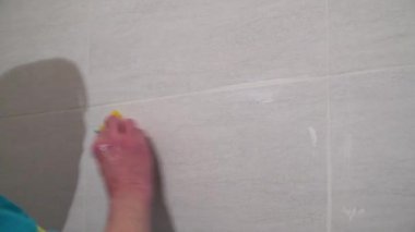 İşçi ıslak sünger karolar arasında dikişleri çöp. Bitirme işleri, ellere odaklan. Kiremit döşeme teknolojisi.
