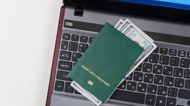 Laptop klavyesinde Amerikan doları olan yeşil pasaport. Online kayıt. Kavram - rüşvet ve yolsuzluk. Üst görünüm