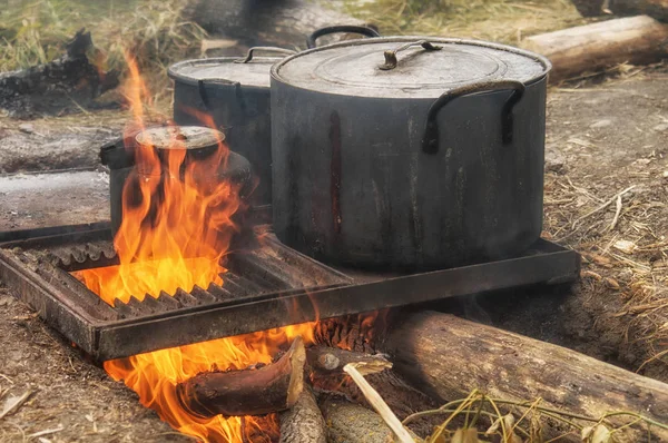 Field kitchen. Saucepan, pot and kettle on fire from the bonfire. Water boils and cooking food in the tourist camp — Stock Photo, Image