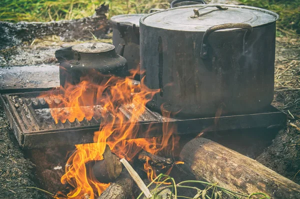 Field kitchen. Saucepan, pot and kettle on fire from the bonfire. Water boils and cooking food in the tourist camp — Stock Photo, Image