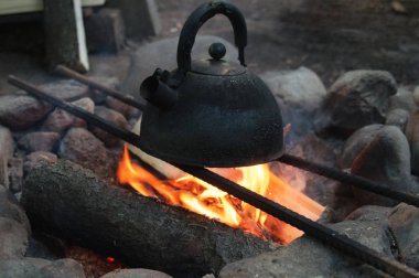 Şenlik ateşi üzerinde turist kaynar su ısıtıcısı. Orman kampında taş Ocak içinde ateş