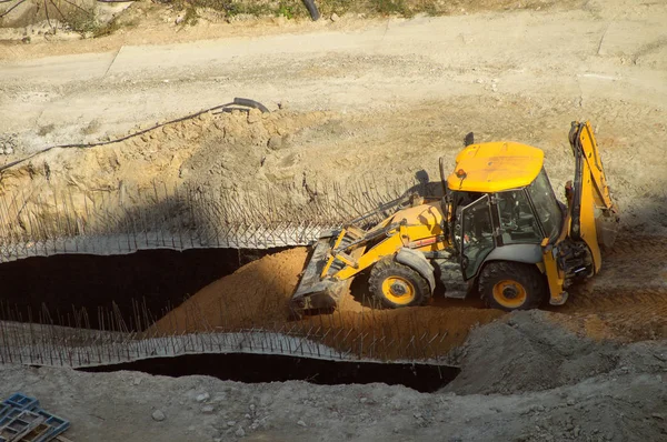 Vista aérea de una excavadora de trabajo en la carrera de arena en la construcción de un edificio de gran altura. La técnica de la máquina alinea la arena para la fundación. Contexto industrial . —  Fotos de Stock