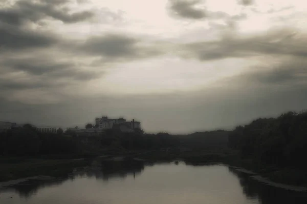 Kasvetli sisli bir nehir üzerinde akşam sis. Arka planda korkutucu binalar.