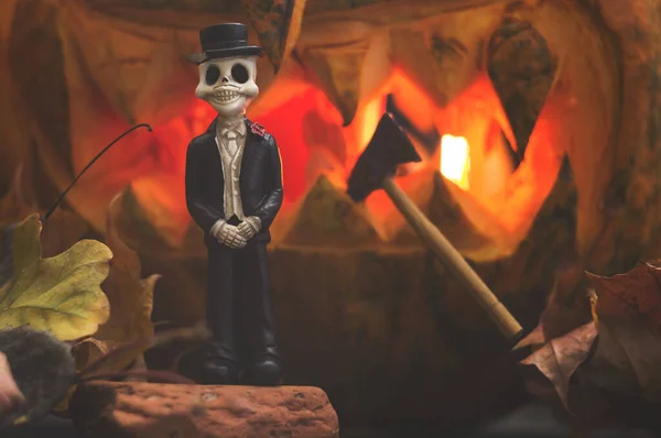 Tag der Toten. die Todesfigur auf dem Hintergrund eines geschnitzten Kürbisses. Miniaturgeschichte zu Halloween in Nahaufnahme — Stockfoto