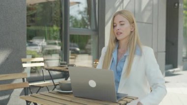 Çalışmayı bitiren serbest çalışan ve dışarıdaki kahvenin üzerinde yansıyan. Profesyonel Kadın Kapanış Dizüstü Bilgisayarının Huzurlu Anı ve Sabahın Işığı Açık Cafe 'de Huzurlu Mola Verme