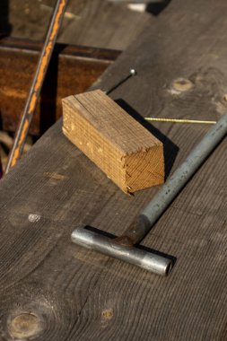 El aletlerinin ve yıpranmış tahtaların üzerindeki çiğ kerestelerin yakın çekimi, geleneksel ahşap ev inşaatını betimliyor..