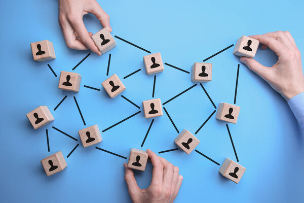 Сетевое сообщество - руки человека помещают деревянные брики с иконой человека на синем фоне, которые соединены между собой. подключенные люди