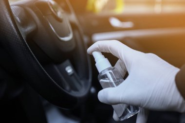 Arabanın içi bakteri ve çeşitli haşerelerden dezenfekte edilmiş. Covid 19 'dan koruma. Adam ellerini tutar ve sıvı püskürtür..