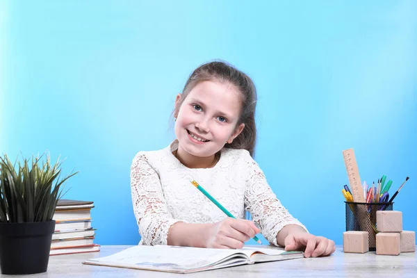 stock image Back to school .Happy cute industrious child is sitting at a desk indoors.He notes in a notebook and smiles at the frame.Kid is learning in class.quarantine.Kid is learning in home