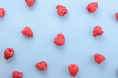 Mavi arka planda ahududu deseni. Düz yaz meyveleri - kırmızı ahududular. Yaratıcı minimalizm.