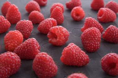 Koyu kayalarda ahududu deseni. Düz yaz meyveleri - kırmızı ahududular. Yaratıcı minimalizm. Ön görünüm.