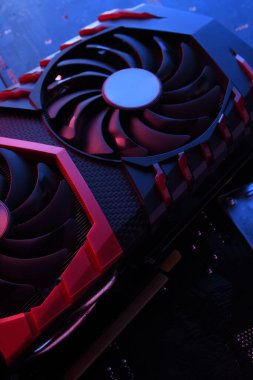 Bilgisayar oyunu grafikleri kartı, devre kartında iki soğutucu olan video oyunu, anakart geçmişi. Yakın plan. Kırmızı-mavi ışıkla.