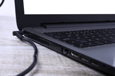 Laptop, bilgisayar duvarın yanındaki bir masada 220 voltluk bir prizden şarj oluyor. Enerji, birikim