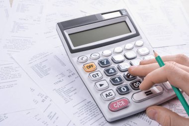 Masa başında hesap makinesi kullanan tanınmayan bir işadamı. Ofisteki maliyeti hesaplayarak not alın. Finans muhasebe kavramı. vergi, alışveriş, maliyet yönetimi.