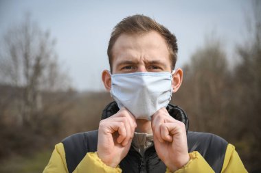Tıbbi maskeli genç ve çekici bir adamın portresi. Coronavirus. COVID-19. 2019-Ncov.medikal maske takıyor..