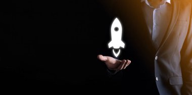 Takım elbiseli iş adamı, roket ikonu üzerinde uçmak için elini uzatıyor. Yeni bir iş kurma kavramı..