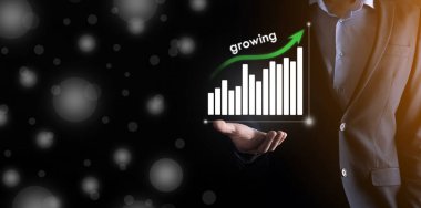 Holografik grafikler ve borsa istatistikleri tutan işadamı kâr elde ediyor. Büyüme planlama ve iş stratejisi kavramı. İyi ekonomi formunun dijital ekran görüntüsü.