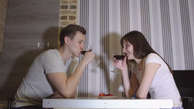 Romantik akşam. Genç bir çift bir masada şarap içme ve öpüşme