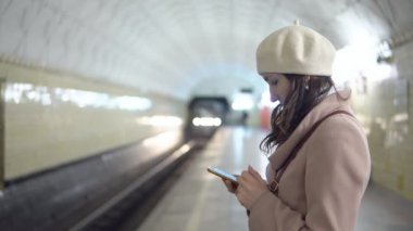 Bir tren bekliyorsun metropilitene bulunan bir telefon ile bir ceket genç kadın