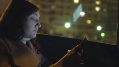 Bir araba ile bir telefon yolcu koltuğunda genç kadın gece şehrin içinden rides