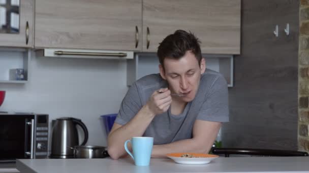 若い男が、眠って、台所でオートブラン朝食シリアル — ストック動画