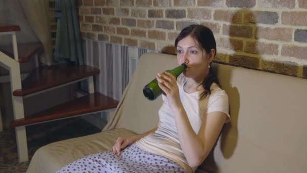 Jeune femme sur canapé buvant de la bière devant la télévision — Video