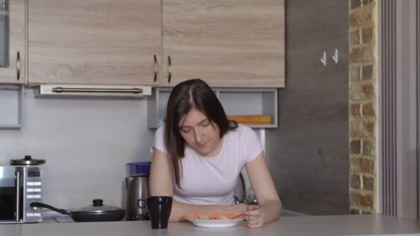 Wanita muda, tertidur, makan di meja di dapur — Stok Video