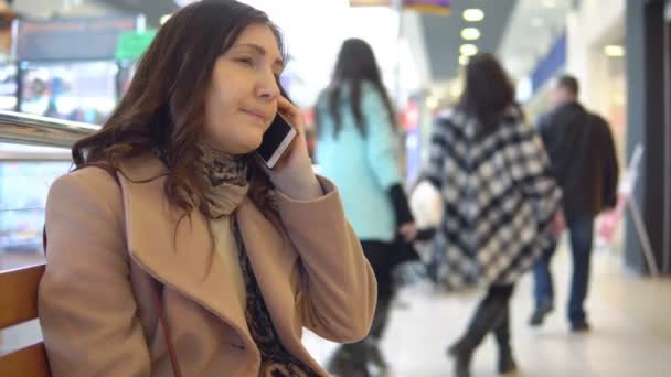 Jeune femme dans un centre commercial parlant au téléphone — Video