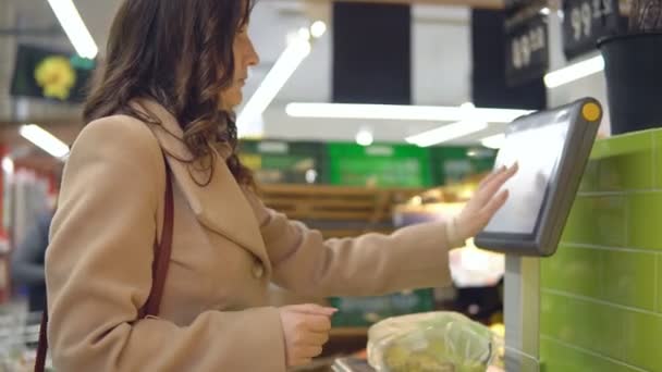 Vrouw met een gewicht van peren in de supermarkt plantaardige sectie — Stockvideo