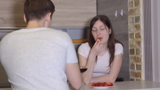 Hombre y mujer en una mesa con vino y fresas. Noche romántica — Vídeos de Stock