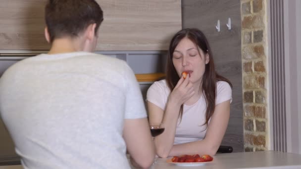 Mann und Frau an einem Tisch mit Wein und Erdbeeren. Romantischer Abend — Stockvideo