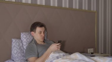 Adam telefon ile yatağa yatıyor
