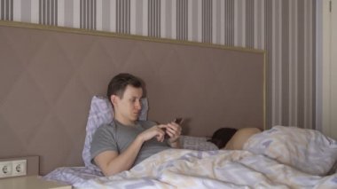 Adam telefon ve çıplak kadın yatakta yatıyordu
